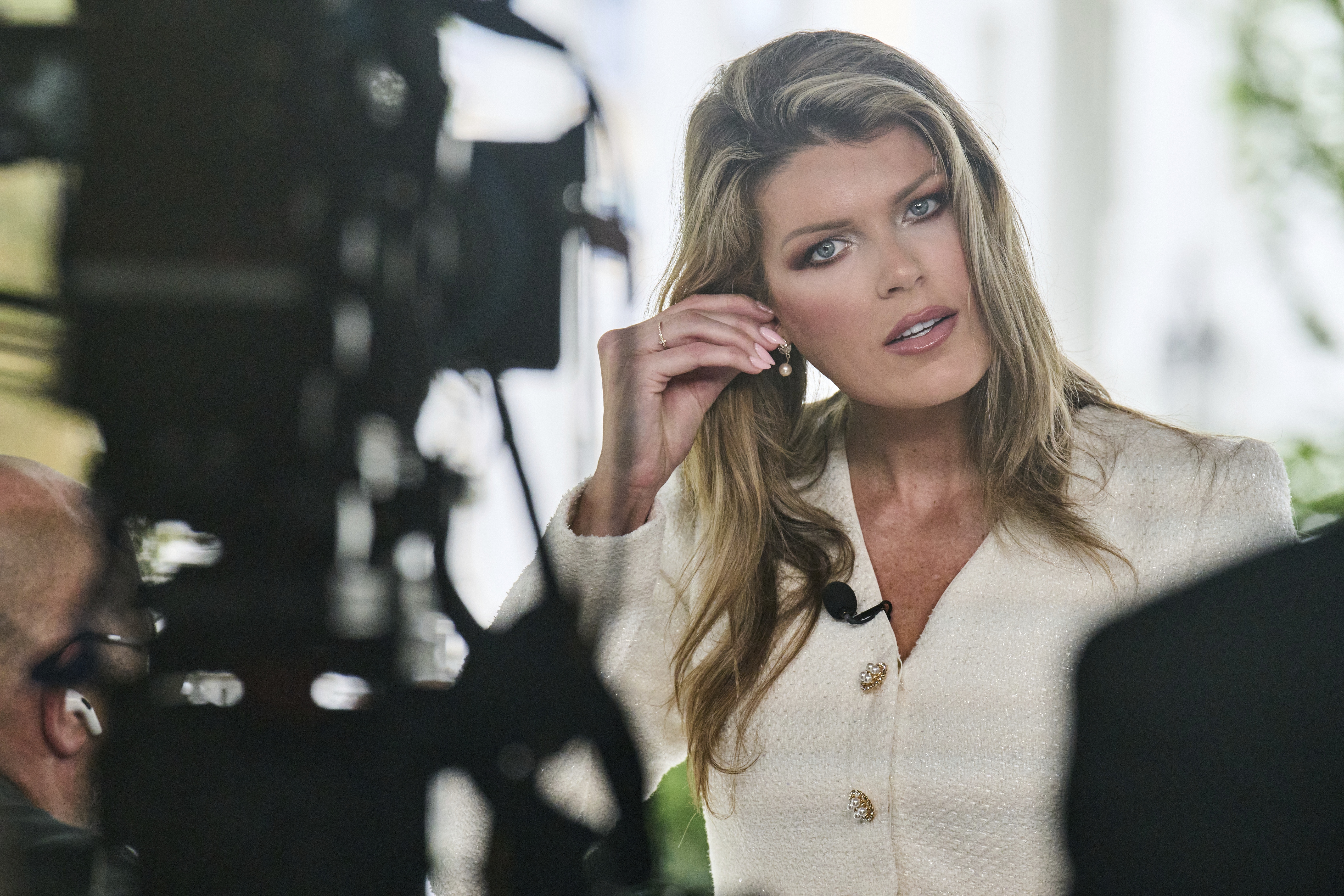 Lindsey Halligan, at the time special assistant to the president, fixes an earring at the end of an interview outside of the White House in August 2025, in Washington.